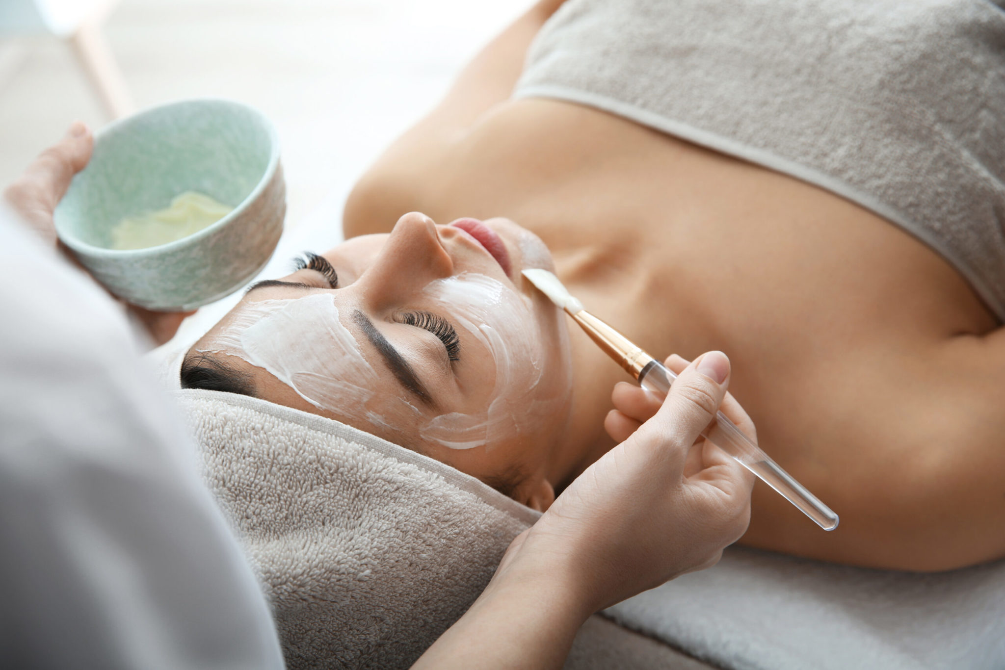 Cosmetologist applying mask on client's face in spa salon, Therapeutic Peptide Therapy | BodySculpt Labs By Sakoon in Omaha NE