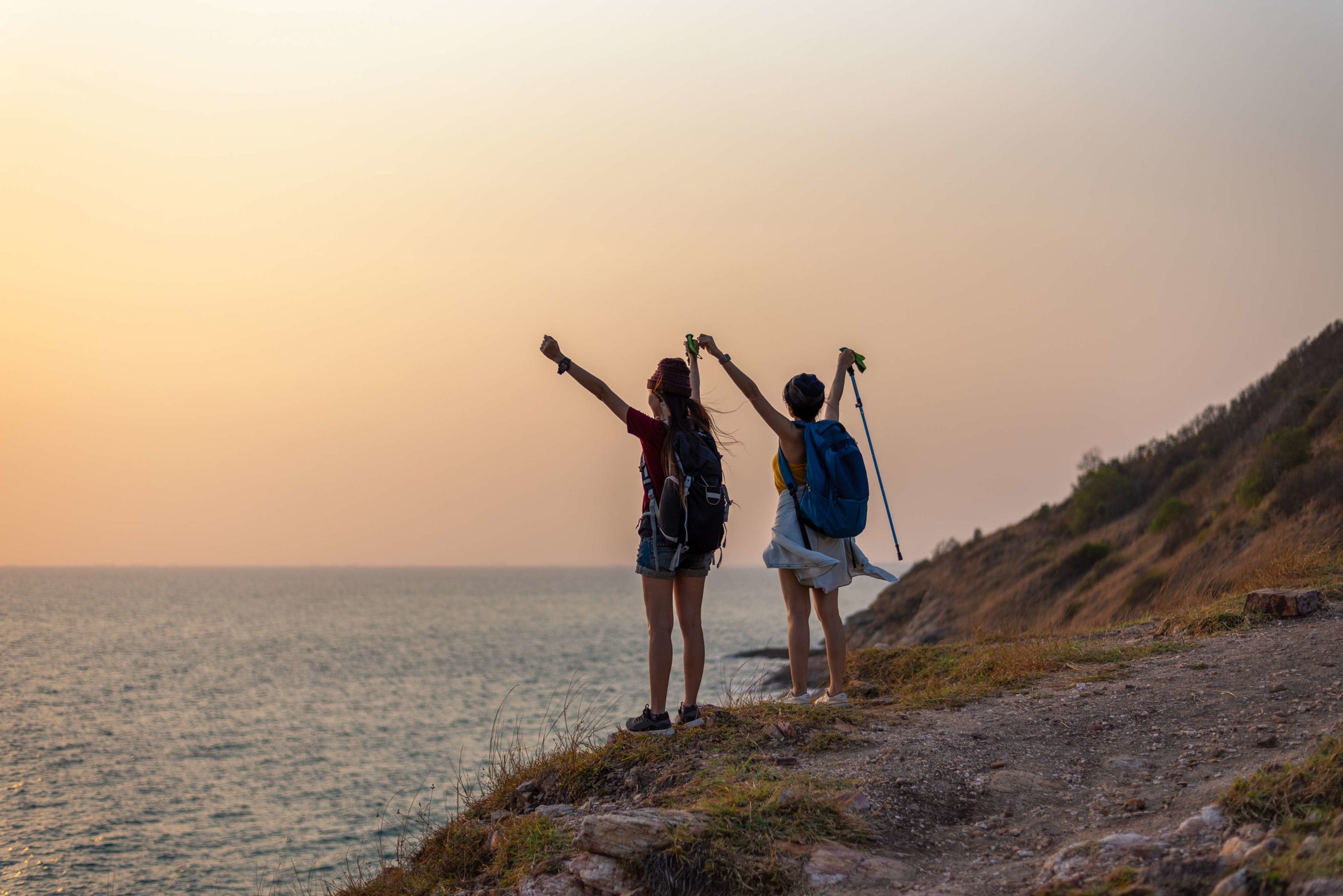 Two Young woman with raised hands standing at seaside mountain | BodySculpt Labs By Sakoon in Omaha NE